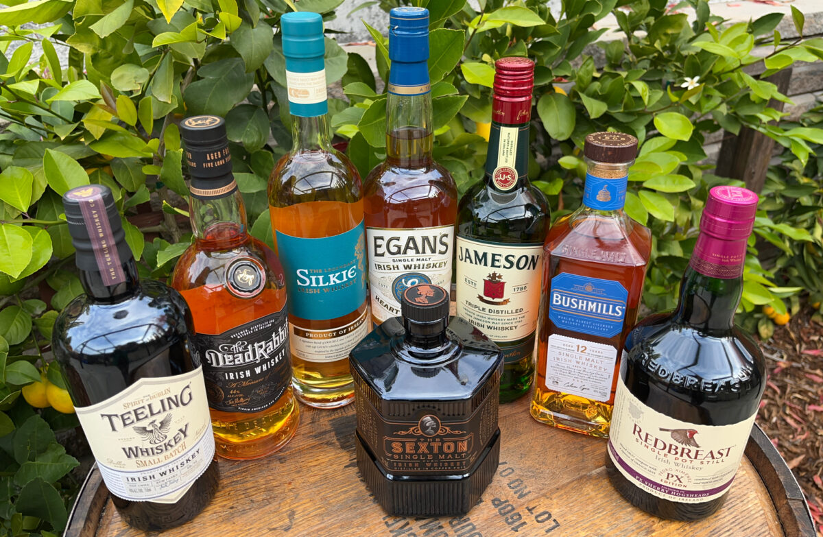 selection of Irish whiskeys that are available in the US pictured atop a Bourbon cask. These casks are used in the aging process of Irish whiskey. Credit IWSA/Andrew Healy